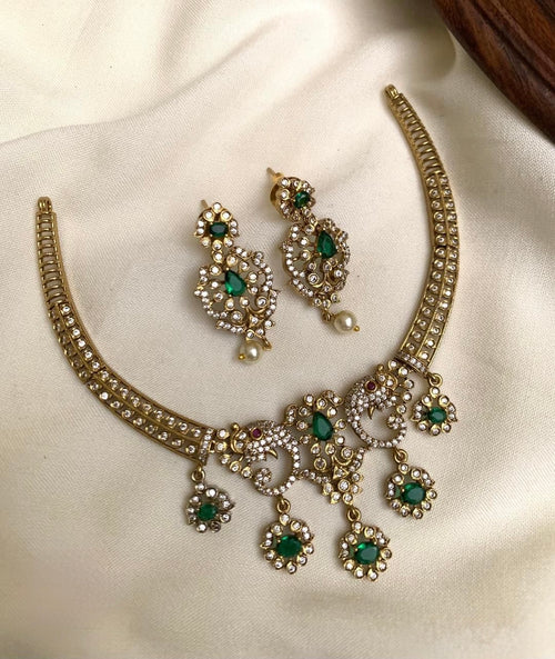 Gold necklace with green gemstones on a white fabric background
